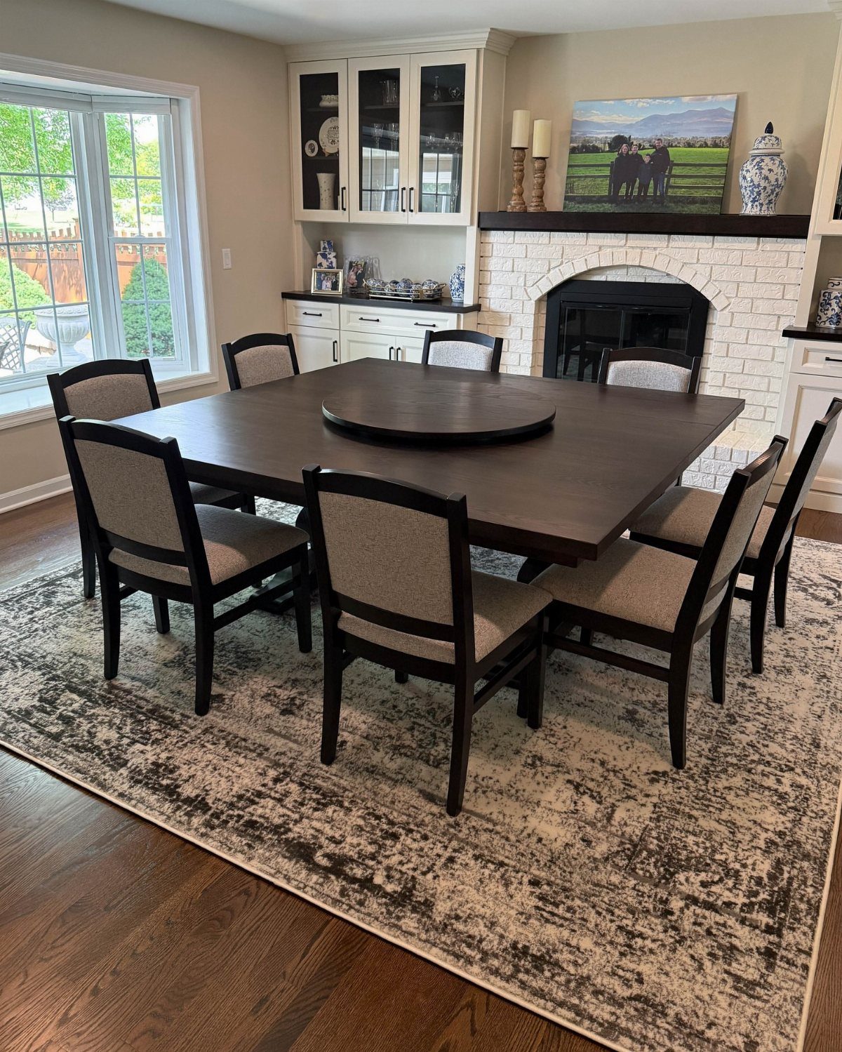 Rectangular dark wood dining table with six upholstered chairs on a patterned rug.
