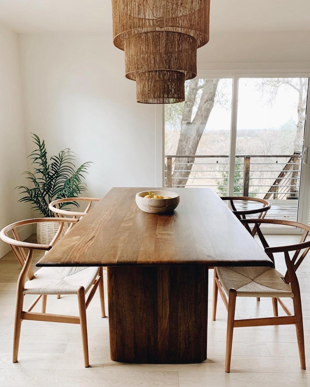 Rectangular dark wood dining table with woven chairs and a tiered pendant light.