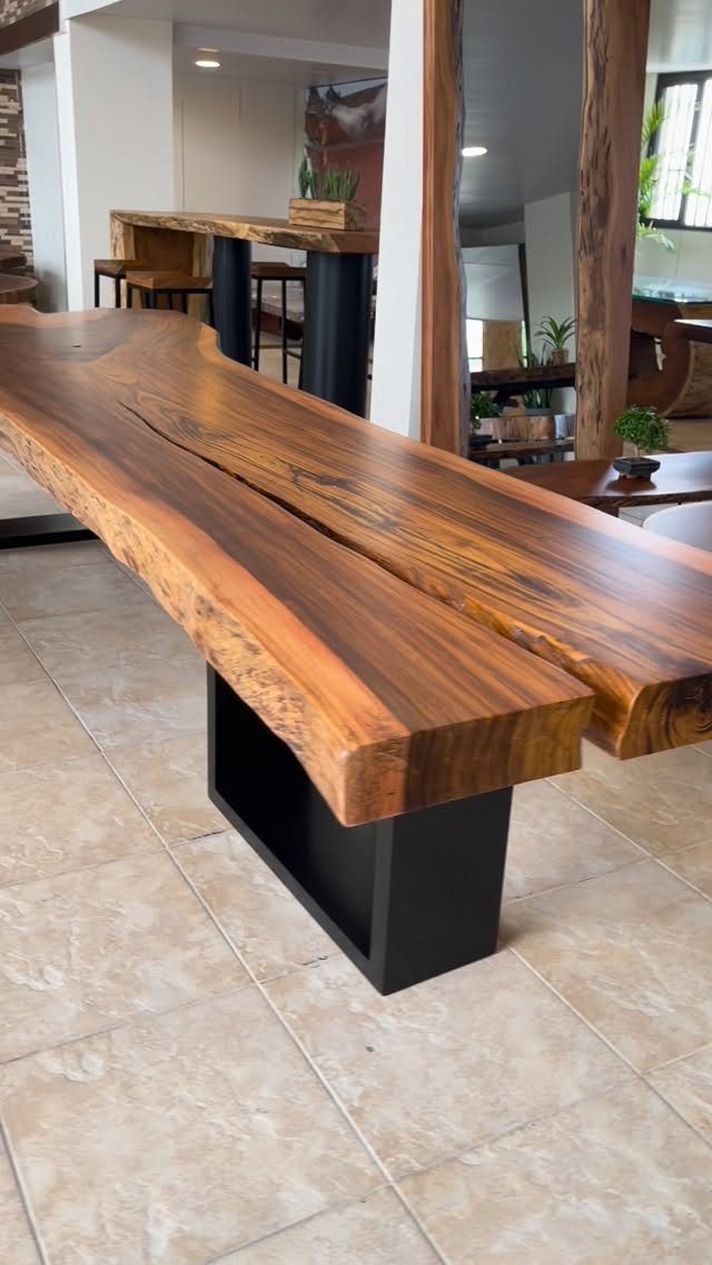 Live-edge wooden dining table with black metal base on light tiled floor