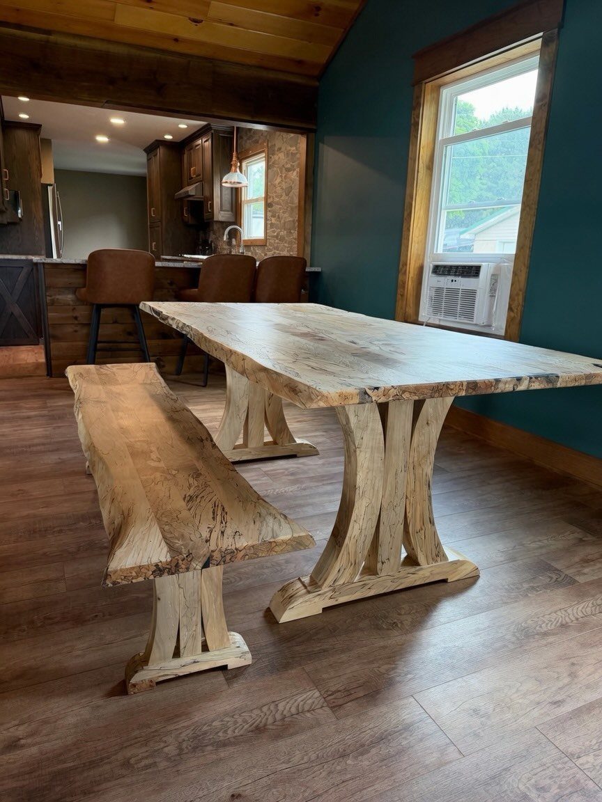 Rustic wooden dining table with live edge and matching bench in a home.