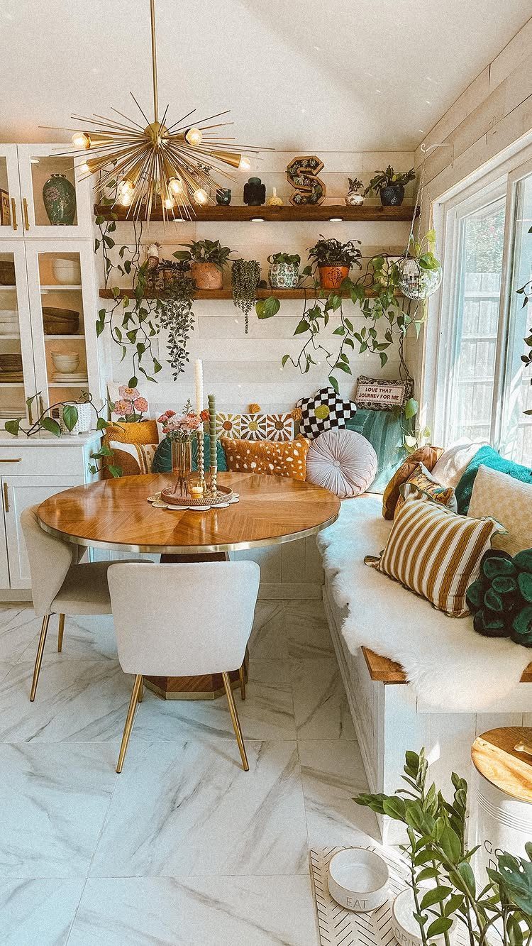 18 Autumn Dining Room Decor Ideas for a Warm and Inviting Space 11 Dining nook with a round wooden table, white bench, colorful pillows, and indoor plants.