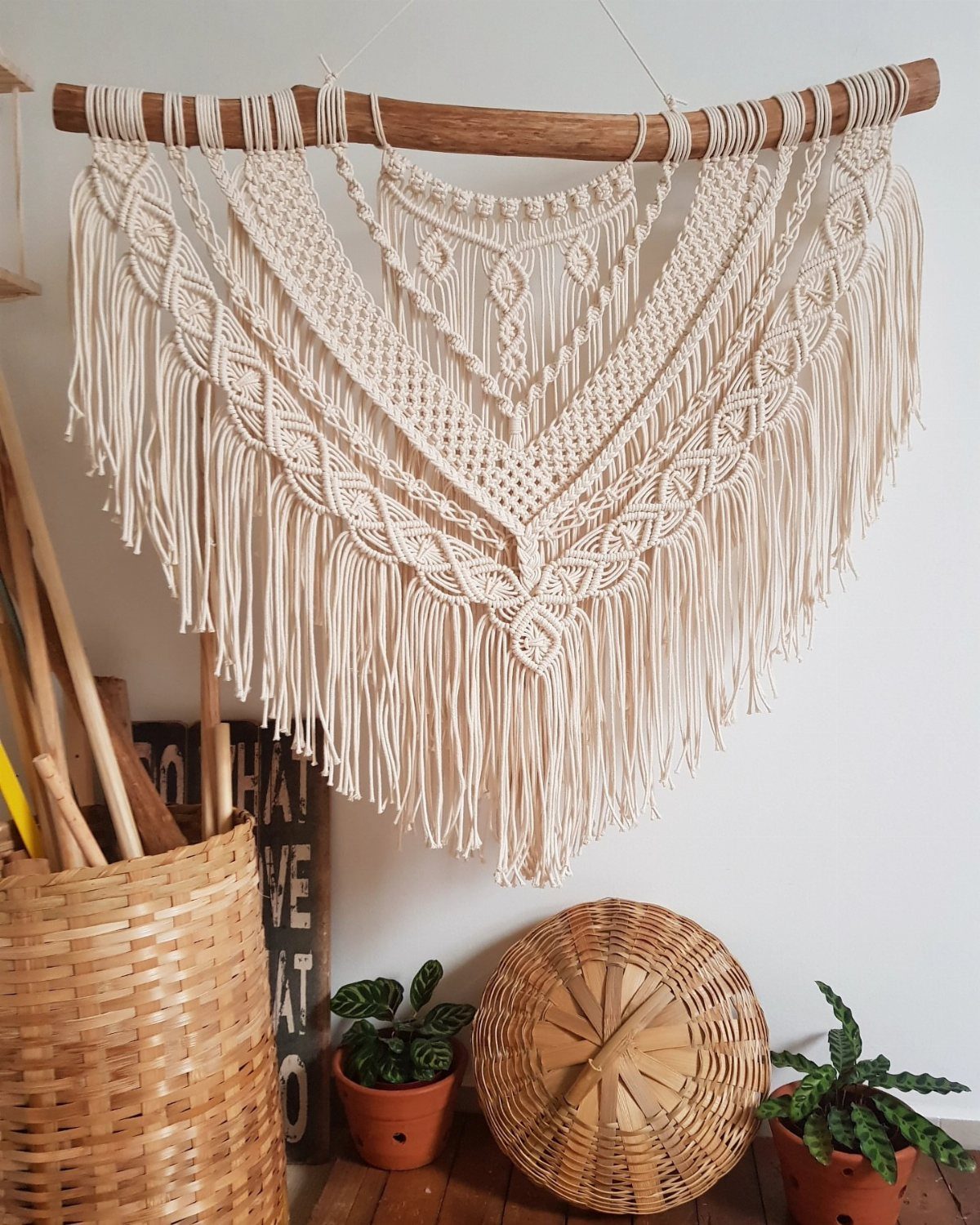 12 Bohemian Chic Dining Room Ideas for Effortless Style 7 Intricate cream macrame wall hanging suspended from a wooden branch above potted plants.