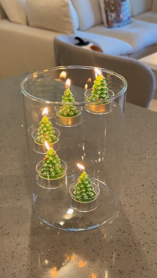 15 Christmas Coffee Table Decor Ideas for a Festive Home 11 Lit green Christmas tree candles inside a clear glass cylinder on a table