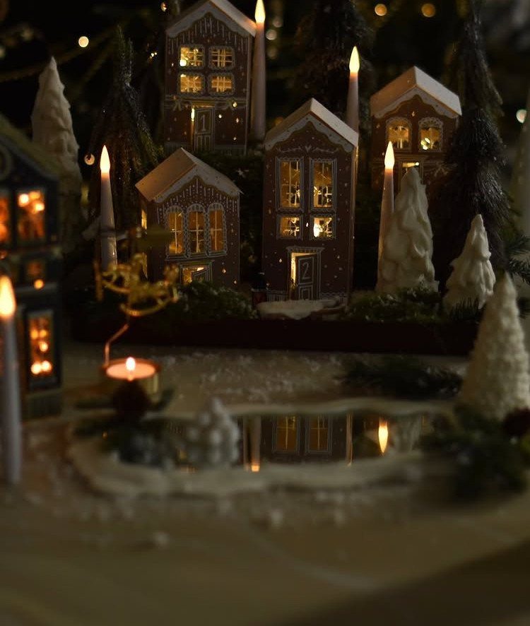 15 Christmas Coffee Table Decor Ideas for a Festive Home 6 Miniature Christmas village with glowing houses, white frosted trees, and tall white candles.