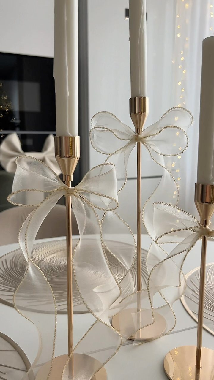 21 Christmas Decor Gift Ideas for the Holidays 18 Gold candle holders with white taper candles and sheer white bows on a table