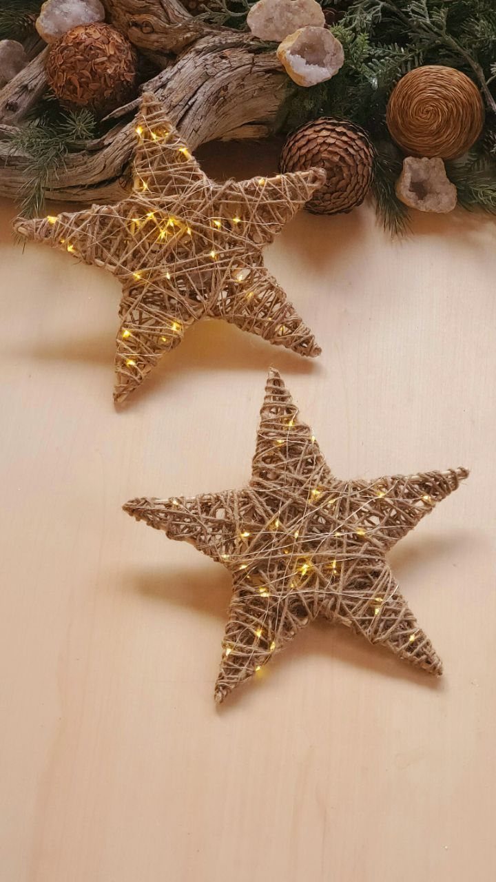 21 Christmas Decor Gift Ideas for the Holidays 16 Two woven twine stars with warm white fairy lights on a wooden surface.