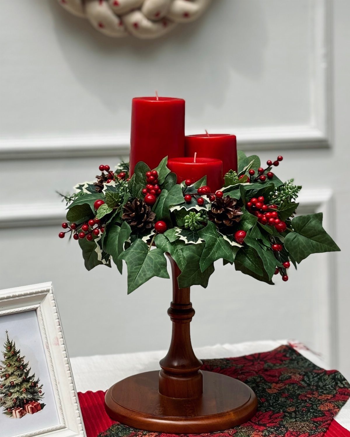 21 Christmas Decor Gift Ideas for the Holidays 3 Red pillar candles in a wooden holder with ivy, berries, and pinecones.