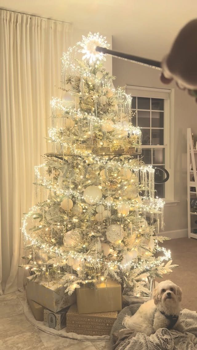 21 Christmas Decor Gift Ideas for the Holidays 2 White and gold Christmas tree with a glowing star topper and a small dog.
