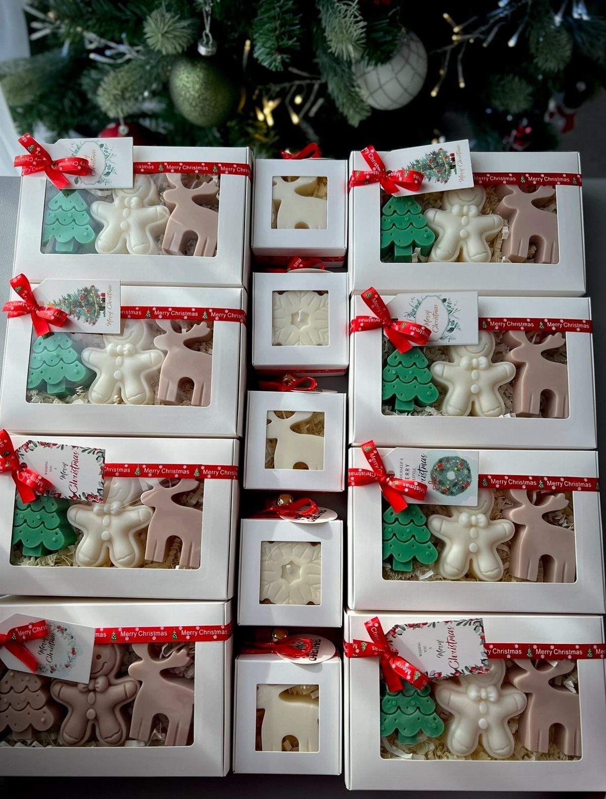 21 Christmas Decor Gift Ideas for the Holidays 4 Shaped Christmas candles in white gift boxes with red ribbons and gift tags.