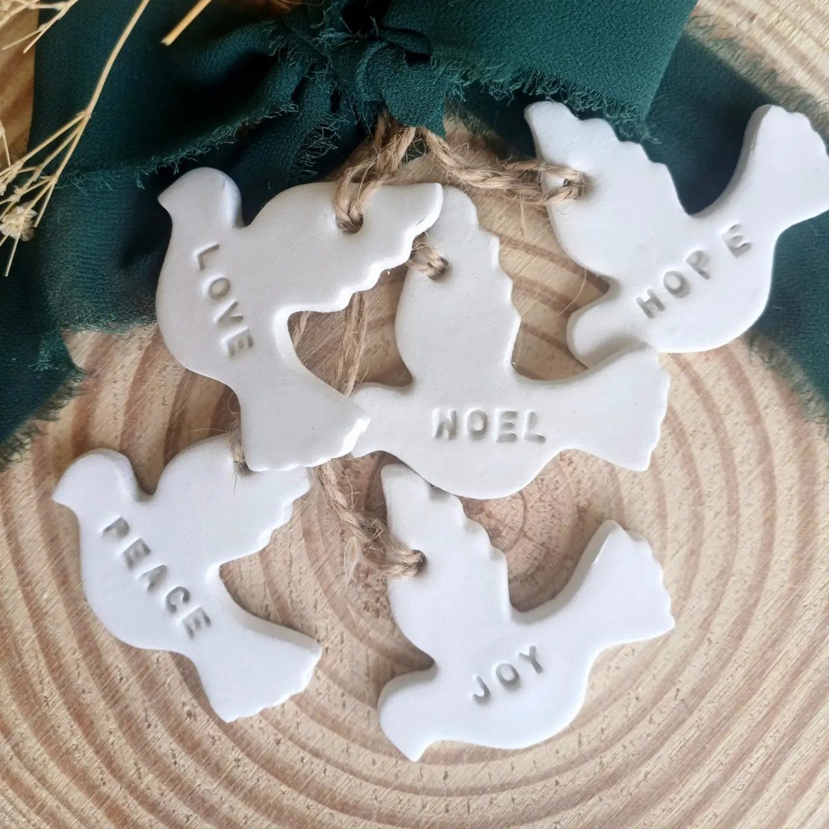 17 Christmas Decor Ideas with White for a Serene Home 12 White ceramic dove ornaments with embossed words on a wooden slice background