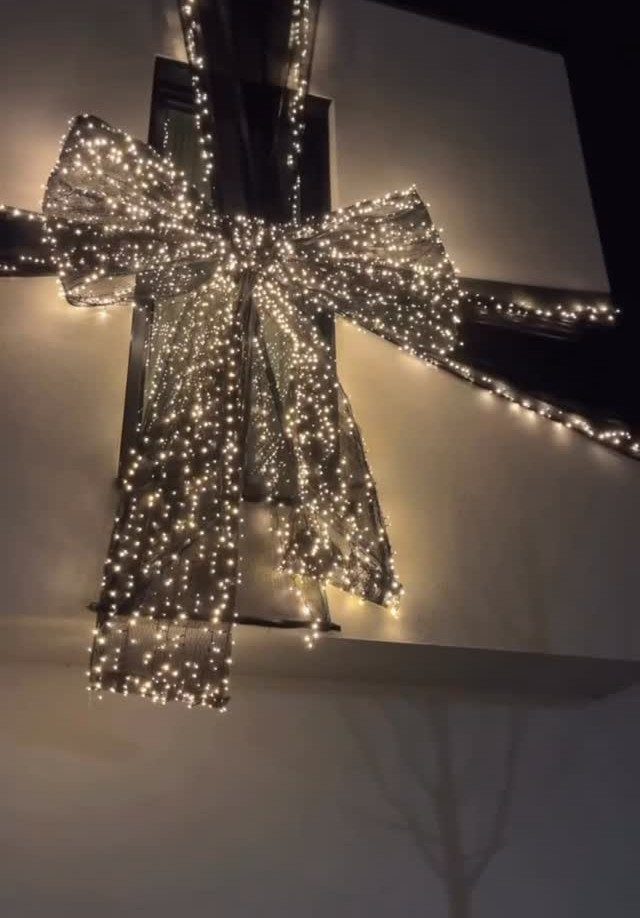 17 Christmas Decor Ideas with White for a Serene Home 17 Large glowing white light bow decorating the exterior of a white building at night