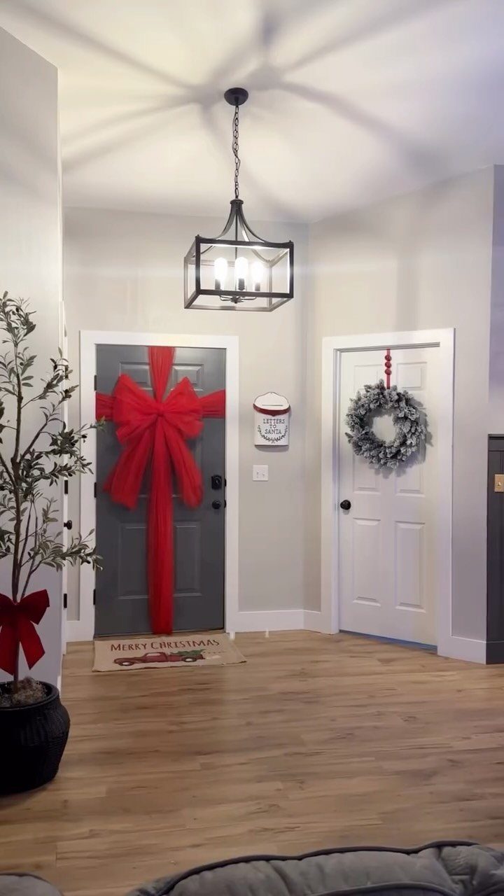 17 Christmas Decor Ideas with White for a Serene Home 8 Entryway with a grey door featuring a red bow and a white wreath.