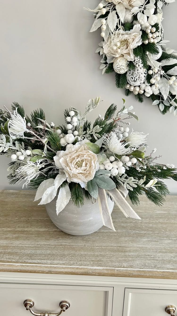 17 Christmas Decor Ideas with White for a Serene Home 11 White floral Christmas centerpiece and a matching white wreath on a neutral wall.