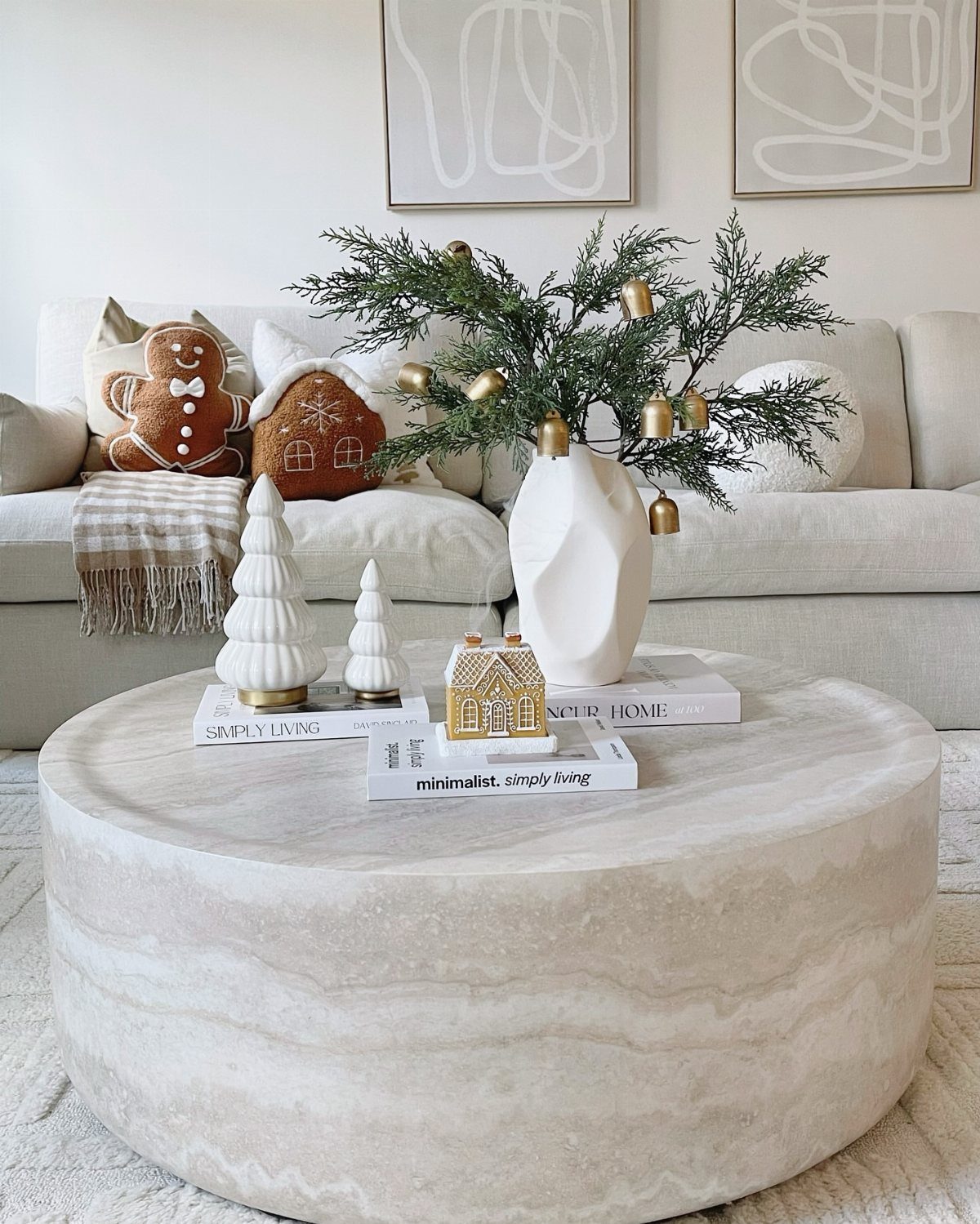 17 Christmas Decor Ideas with White for a Serene Home 4 White marble coffee table with ceramic trees, gold house, and pine branches in vase.