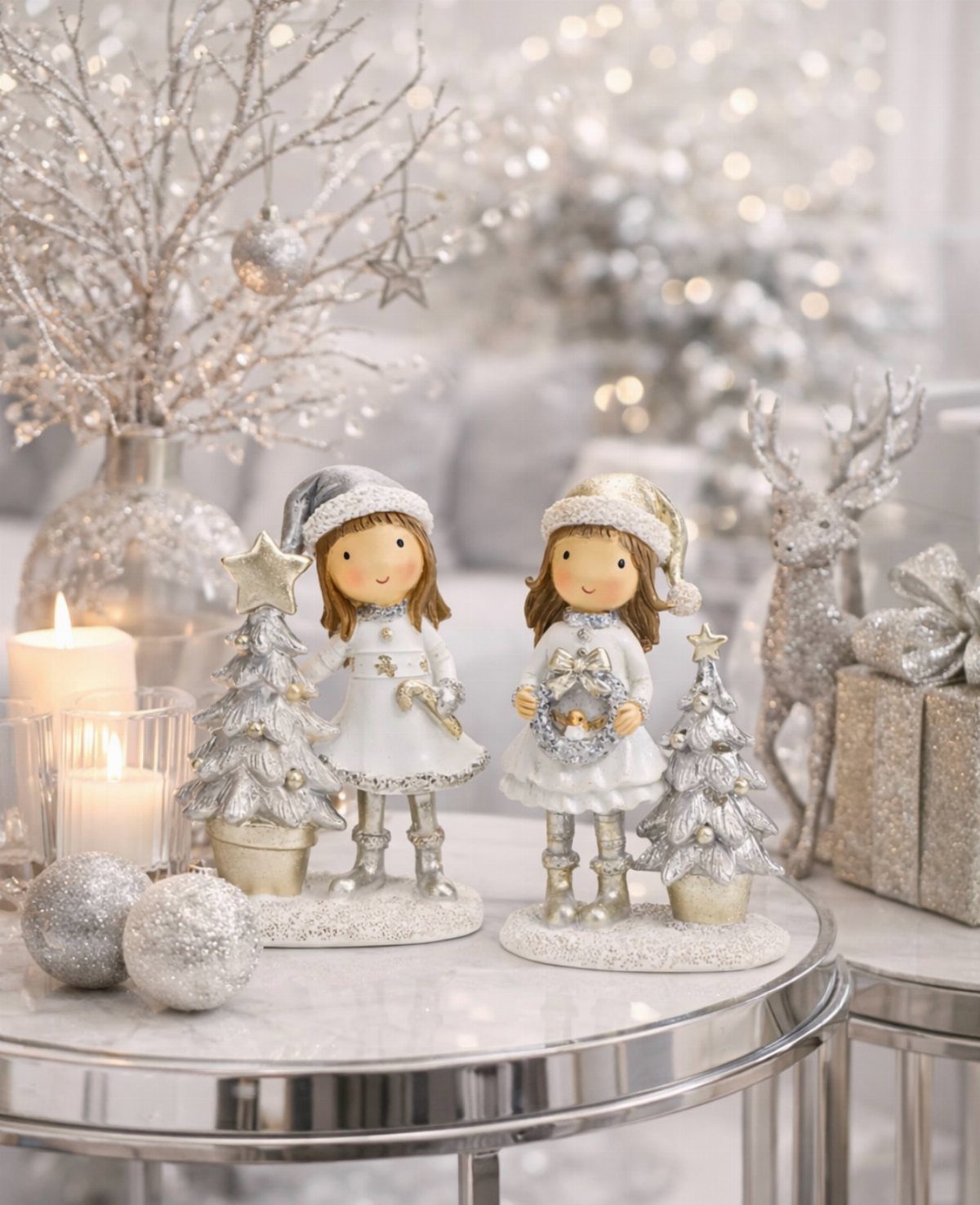 17 Christmas Decor Ideas with White for a Serene Home 2 Winter figurines and silver glitter decorations on a white marble table with candles.