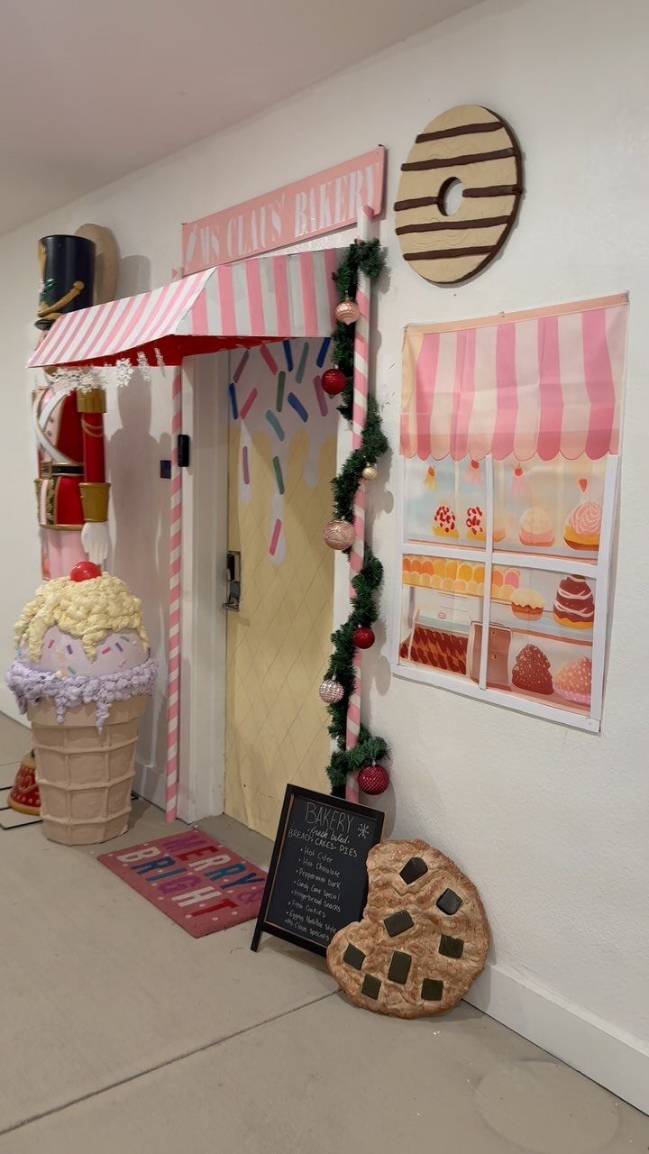 16 Christmas Decorations for Office Spaces That Shine 15 Bakery themed office decorations with a pink awning, giant cupcake, and Christmas garland.
