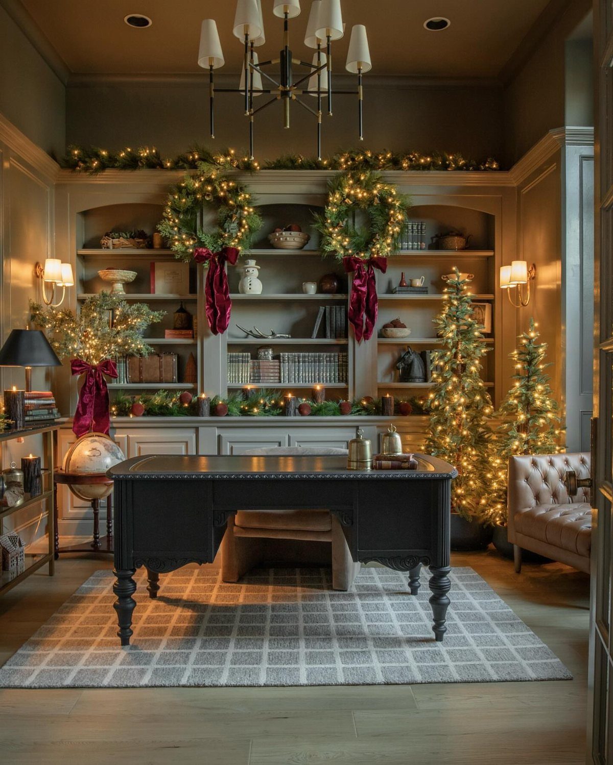 16 Christmas Decorations for Office Spaces That Shine 4 Decorated home office with a dark desk, Christmas trees, and festive garlands.