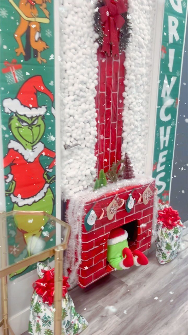 16 Christmas Decorations for Office Spaces That Shine 16 Grinch themed Christmas display with a red faux fireplace and white fluffy snow walls.