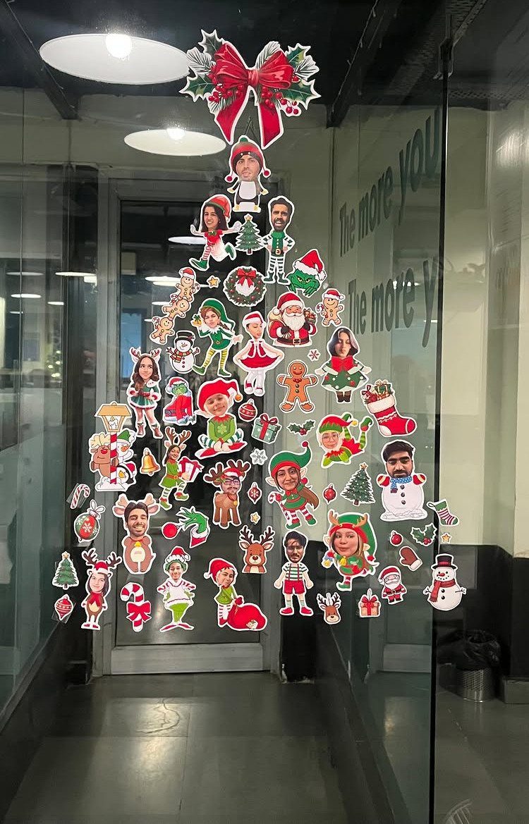 16 Christmas Decorations for Office Spaces That Shine 14 Christmas tree made of photo cut-outs on a glass office door in a hallway