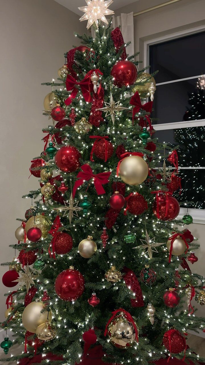 Christmas tree decorated with red and gold ornaments, bows, and glowing white lights.