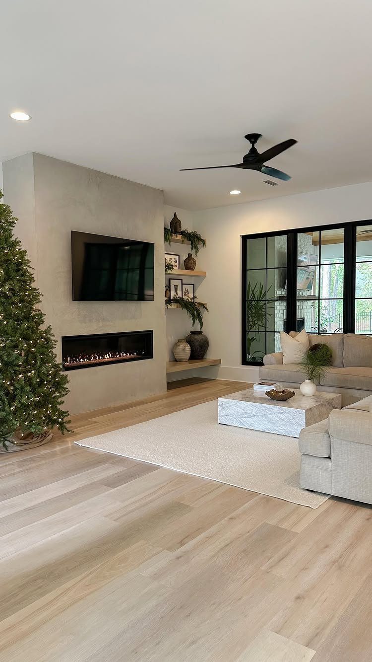 Modern living room with a concrete wall, linear fireplace, and a decorated Christmas tree.