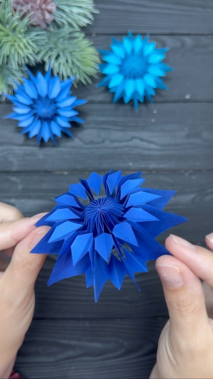 20 Christmas Decorations to Make at Home in 2026 8 Blue 3D folded paper star ornaments on a dark wooden background.