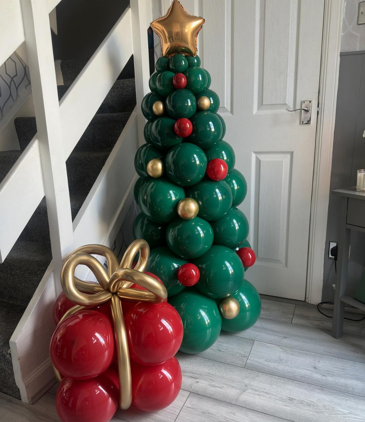 20 Christmas Decorations to Make at Home in 2026 13 Balloon Christmas tree made of green, red, and gold balloons with a star topper.