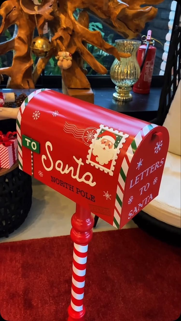20 Christmas Decorations to Make at Home in 2026 16 Red decorative Santa mailbox on a striped post standing on a red rug.