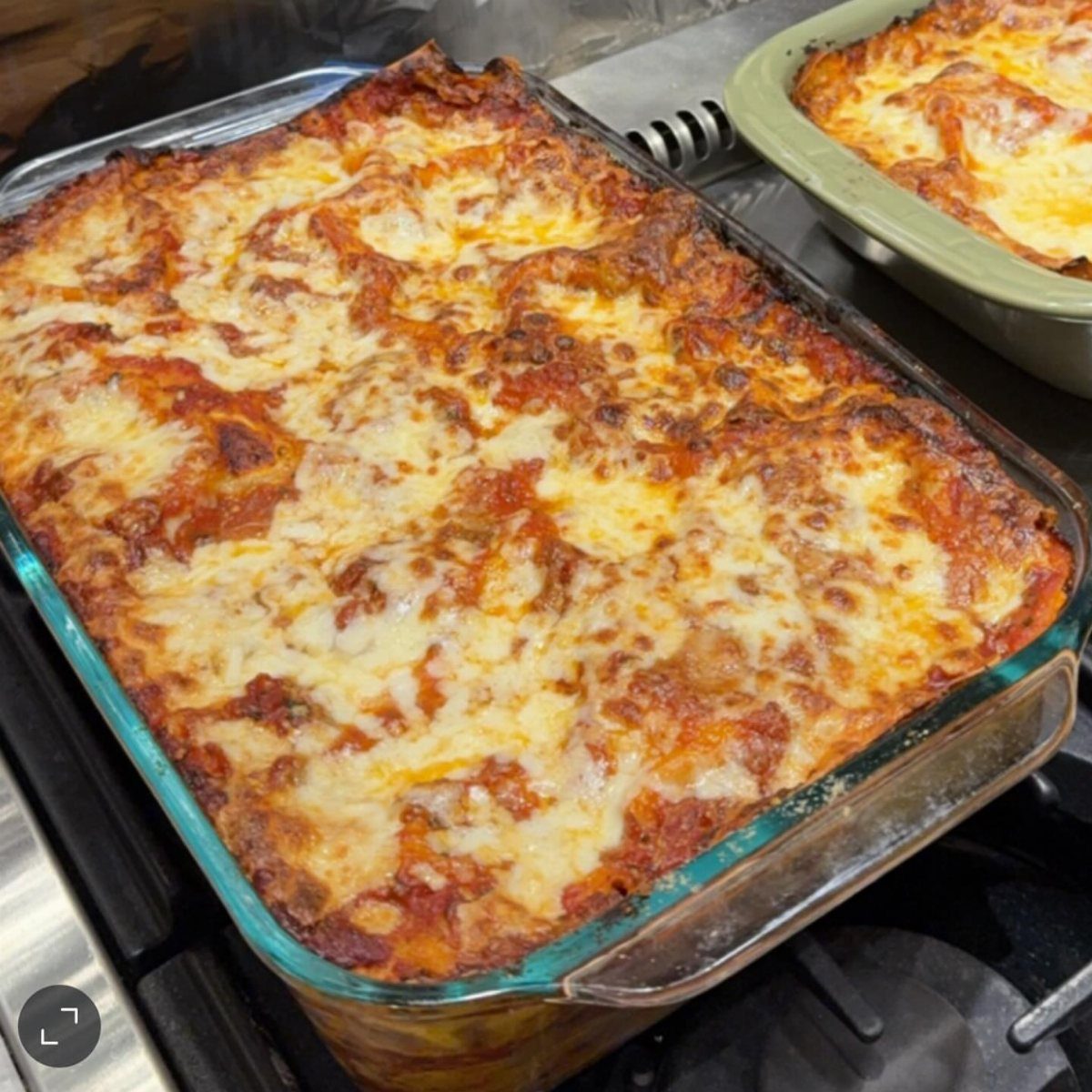 15 Christmas Dinner Party Ideas for a Festive Celebration 9 Baked lasagna with melted browned cheese in a glass baking dish on a stove.