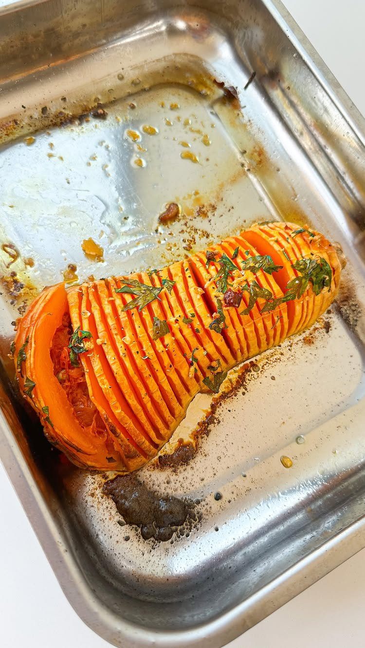 15 Christmas Dinner Party Ideas for a Festive Celebration 11 Roasted hasselback butternut squash with honey glaze and herbs in a metal pan.
