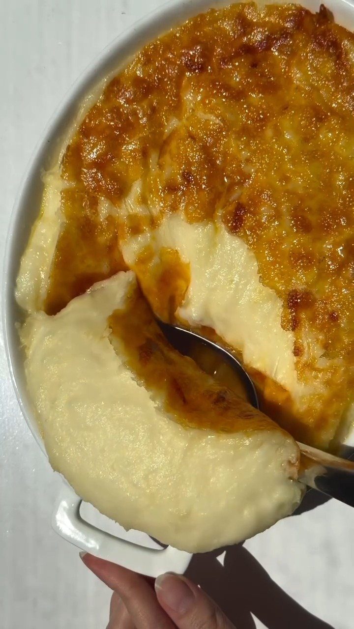 15 Christmas Dinner Party Ideas for a Festive Celebration 10 Mashed potato casserole with melted cheese crust being scooped from a white dish.