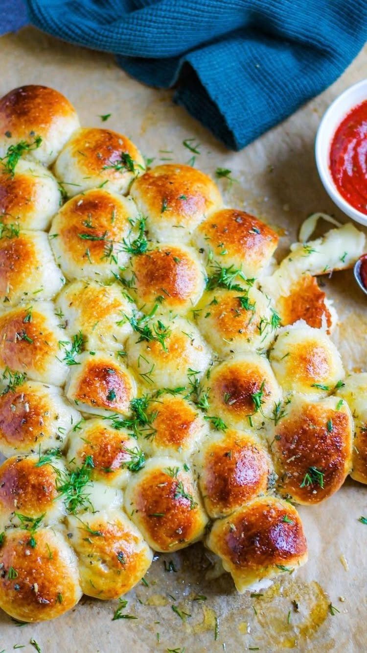 15 Christmas Dinner Party Ideas for a Festive Celebration 15 Christmas tree shaped pull-apart bread rolls garnished with dill and served with red sauce.