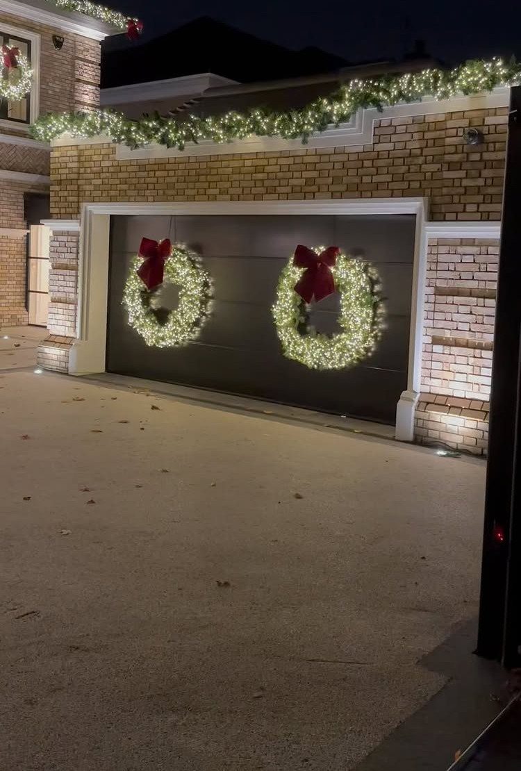 23 Christmas House Decorations Ideas for a Festive Home 14 Two lit Christmas wreaths with red bows on a dark garage door.