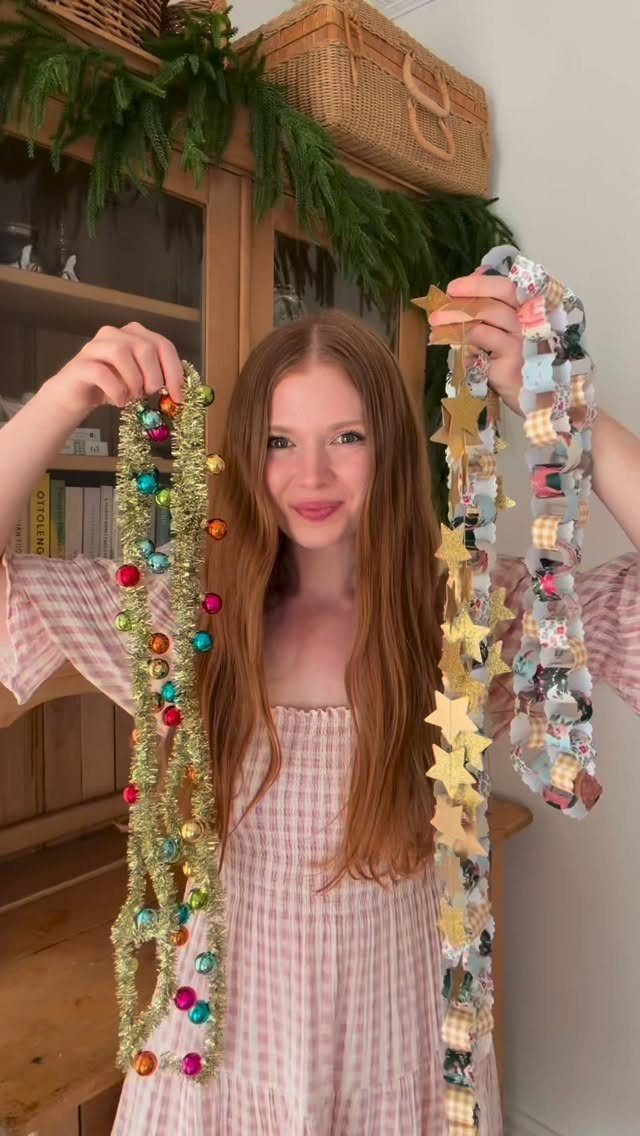 23 Christmas House Decorations Ideas for a Festive Home 1 Woman holding a colorful bauble garland and a handmade paper star garland.