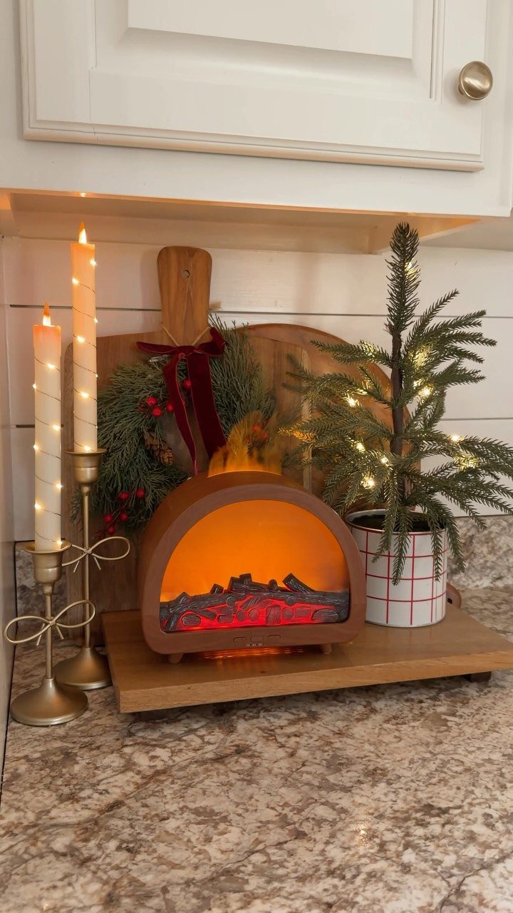 23 Christmas House Decorations Ideas for a Festive Home 12 Small electric fireplace ornament with candles and a mini Christmas tree on a counter