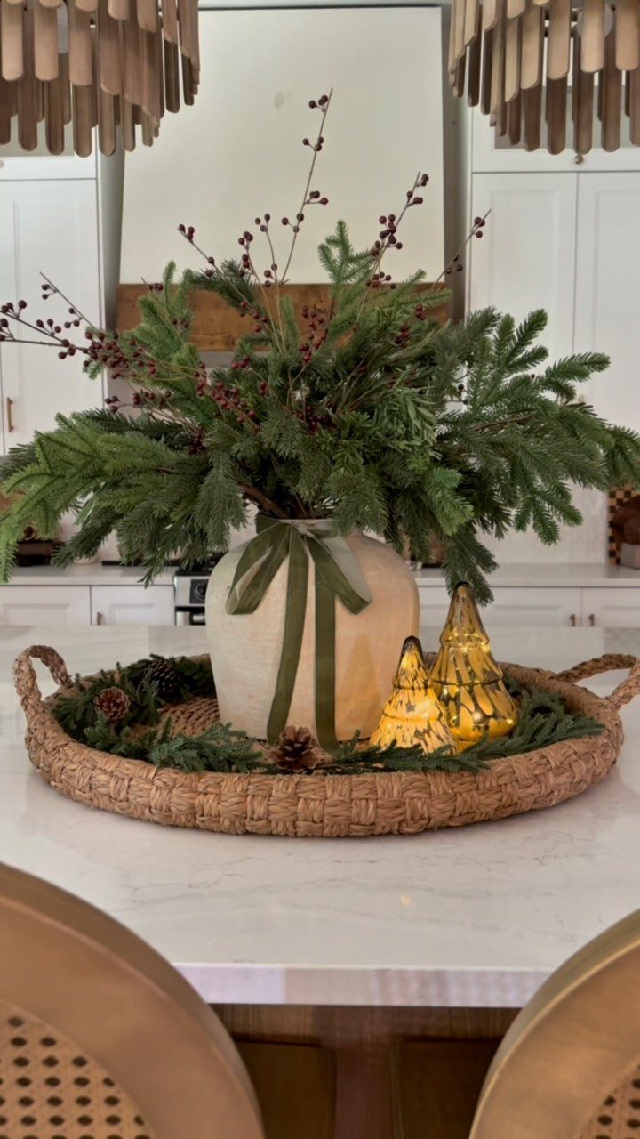 23 Christmas House Decorations Ideas for a Festive Home 6 Evergreen branches and red berries in a vase on a woven tray with gold lights.