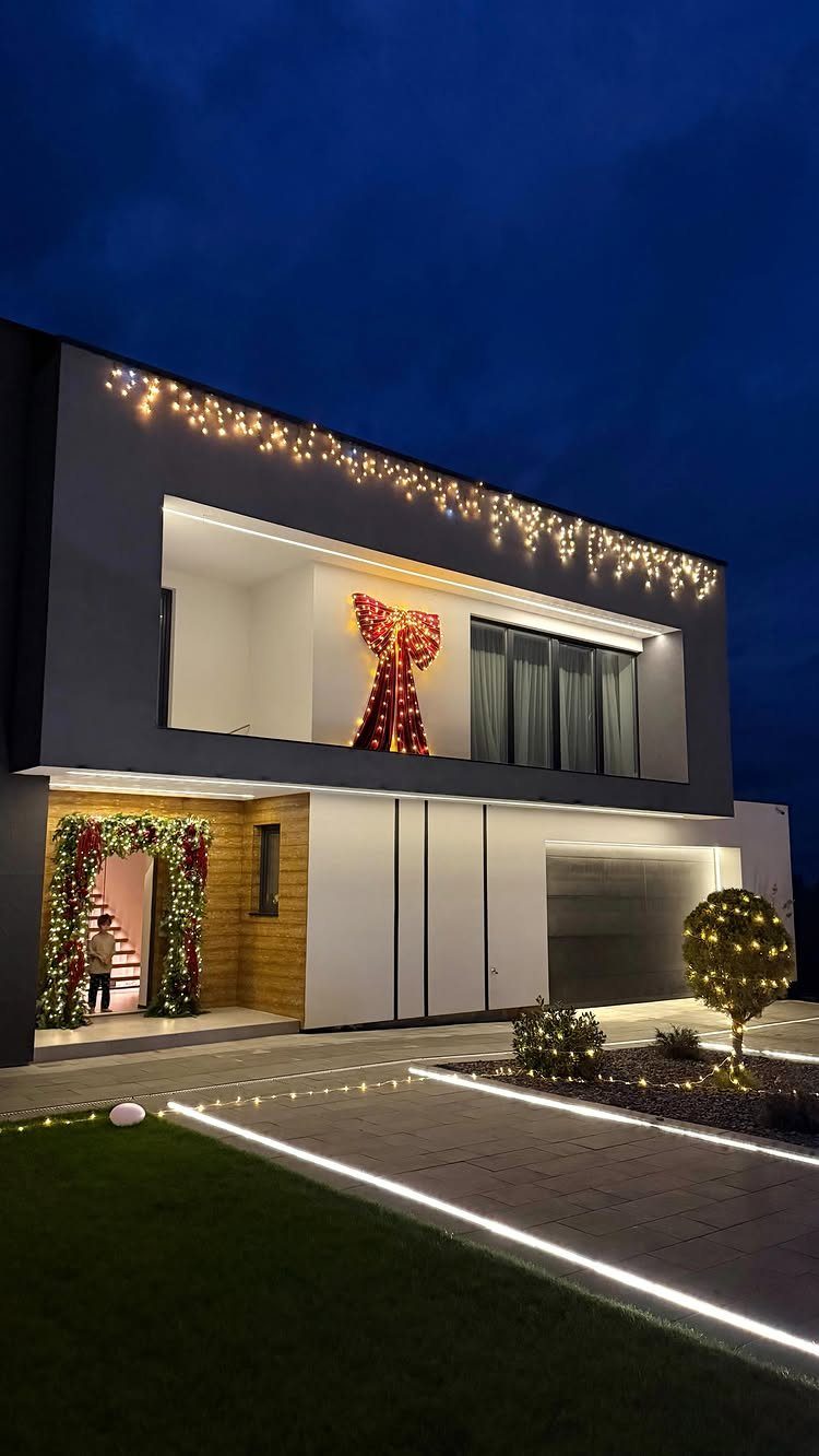 23 Christmas House Decorations Ideas for a Festive Home 10 Modern grey house with Christmas lights, a large red bow, and lit greenery arch.