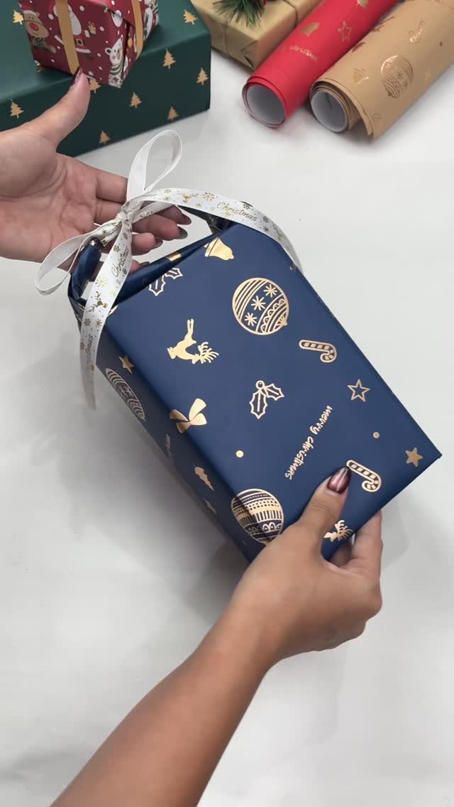 23 Christmas House Decorations Ideas for a Festive Home 9 Navy blue wrapped Christmas gift with gold patterns held by two hands.