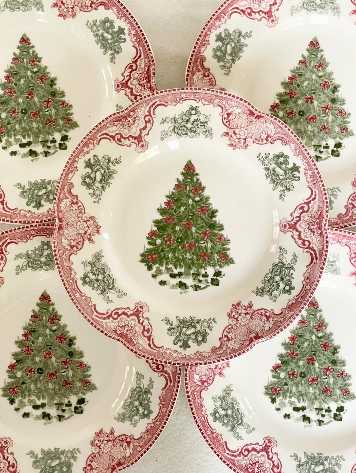 33 Christmas Party Decor Ideas to Bring the Holiday Magic 12 White ceramic plates featuring a green Christmas tree and red ornate borders.