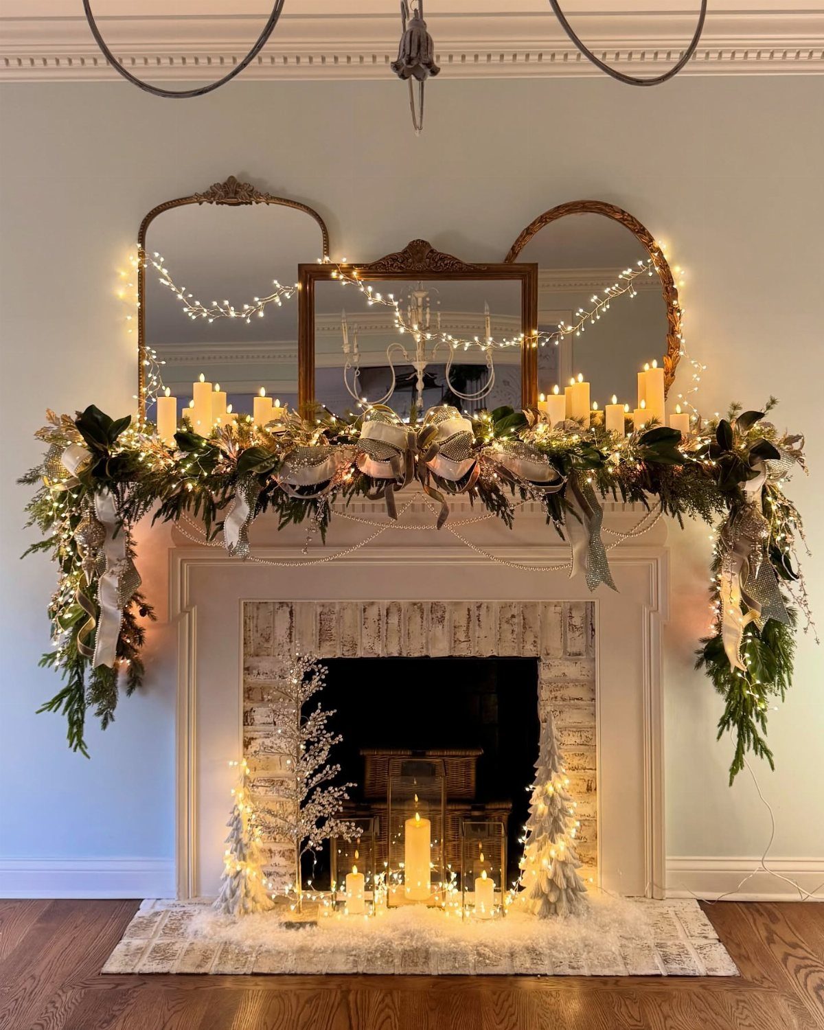 33 Christmas Party Decor Ideas to Bring the Holiday Magic 5 Fireplace mantel decorated with green garland, glowing string lights, and white pillar candles.