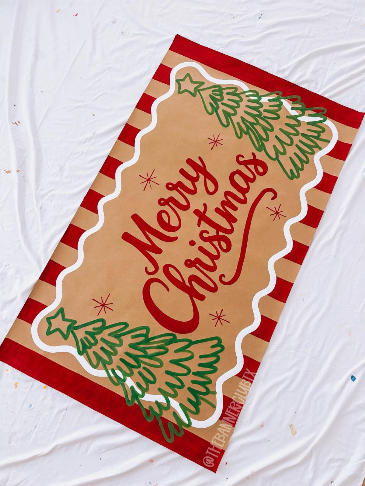 33 Christmas Party Decor Ideas to Bring the Holiday Magic 9 Merry Christmas banner with red cursive text and green trees on tan background.