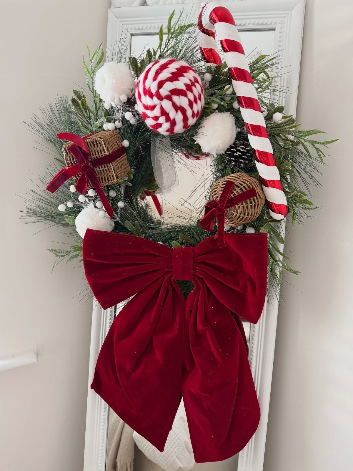 33 Christmas Party Decor Ideas to Bring the Holiday Magic 7 Festive Christmas wreath with red velvet bow, peppermint candies, and a large candy cane.