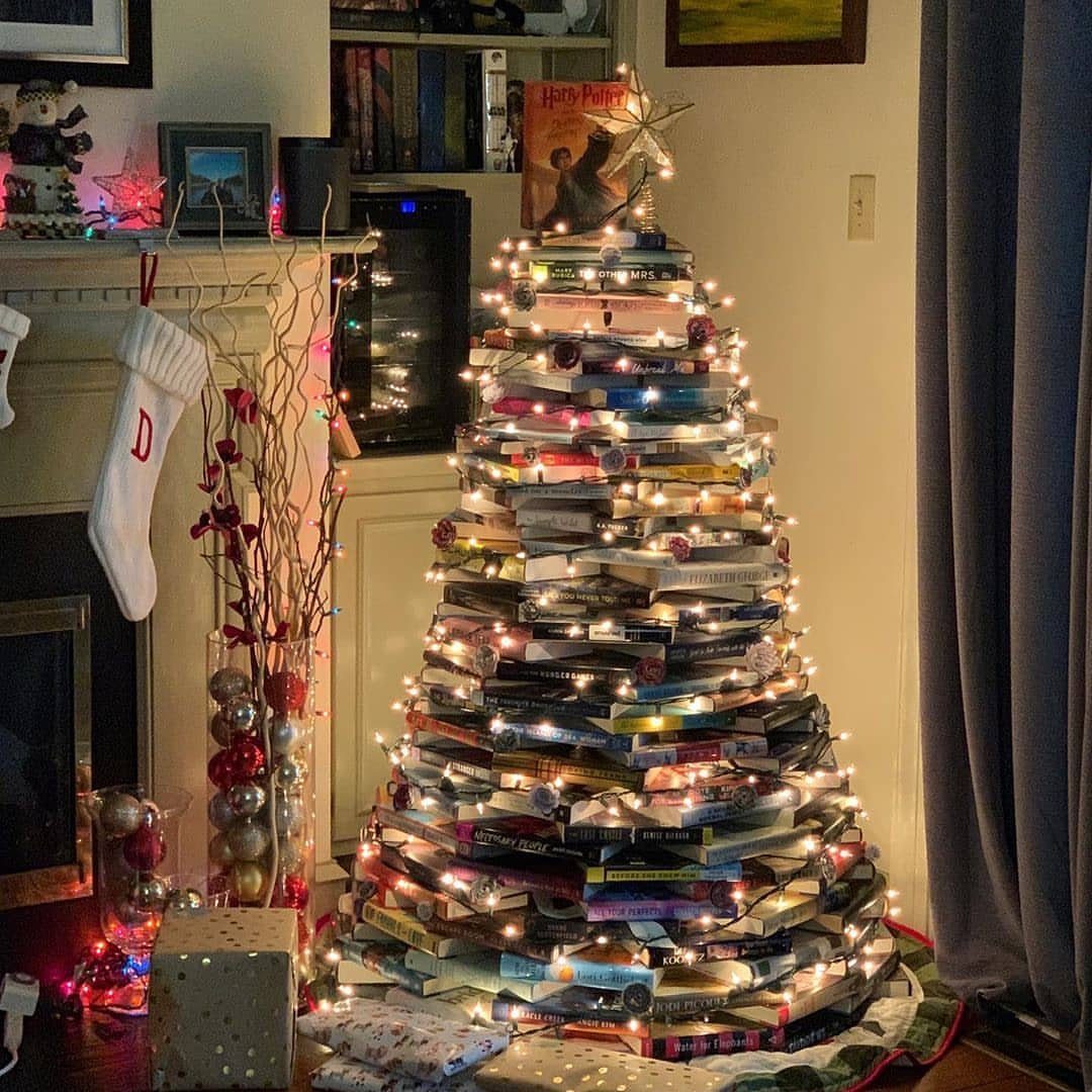 Christmas tree made of stacked books decorated with fairy lights and a gold star.