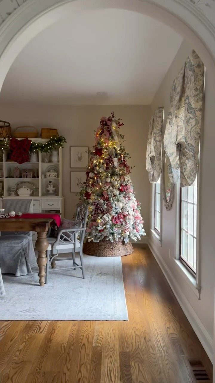Decorated Christmas tree with red and pink ornaments in a rustic cottage room.