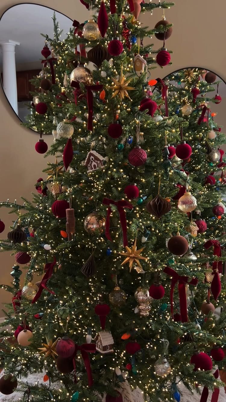 Christmas tree decorated with deep red velvet ribbons, burgundy ornaments, and gold stars.