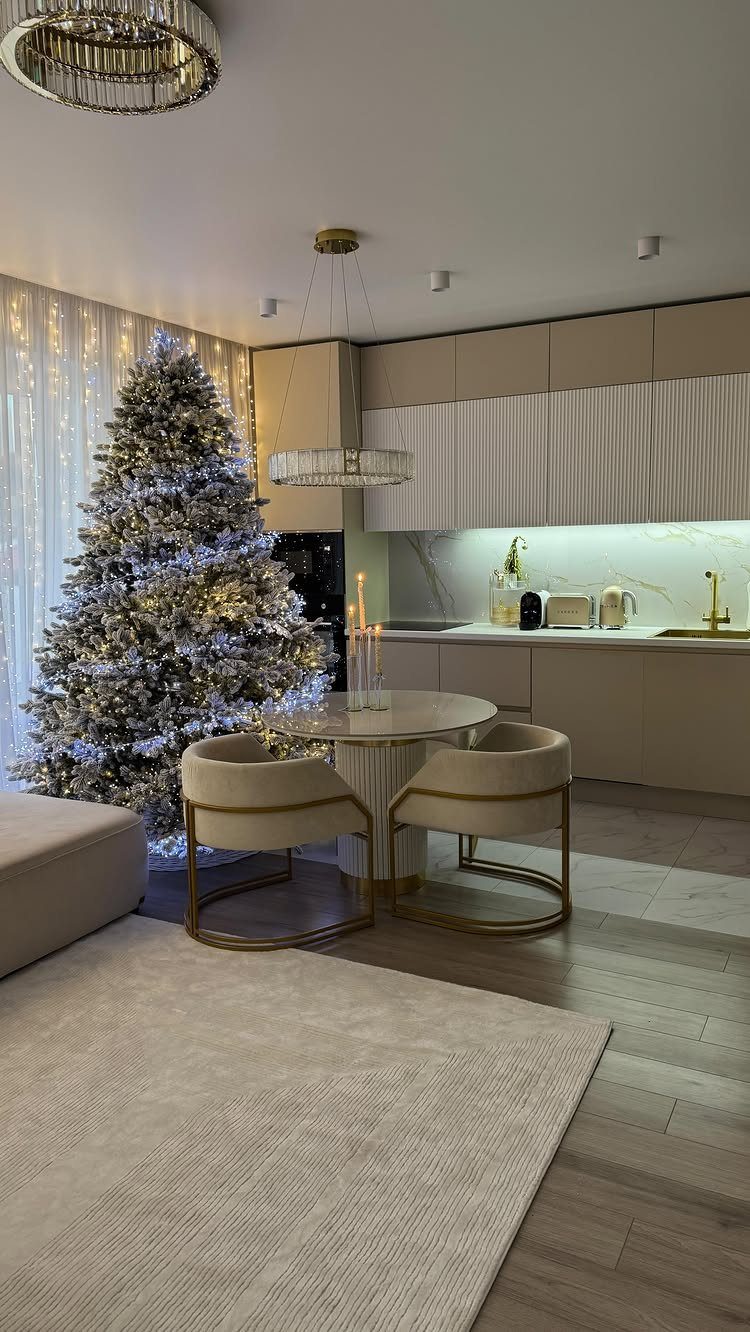 Frosted white Christmas tree with twinkling lights in a modern beige kitchen setting.