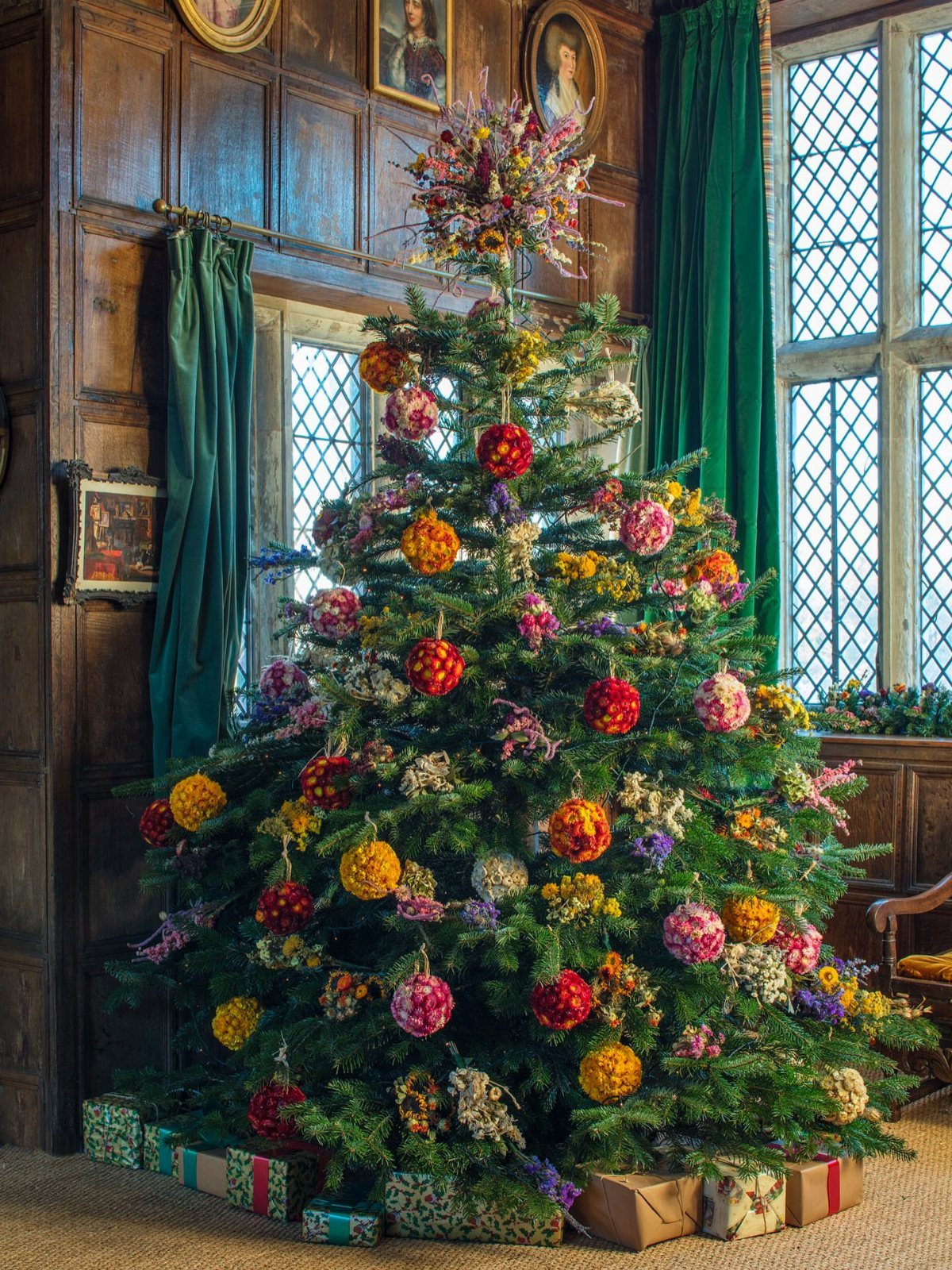 Christmas tree decorated with colorful floral ornaments and a large flower topper.