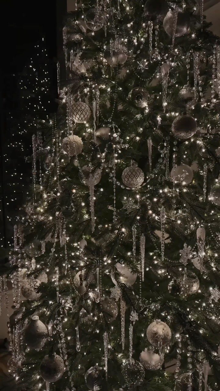 Christmas tree decorated with silver ornaments, white lights, and shimmering icicle pendants.
