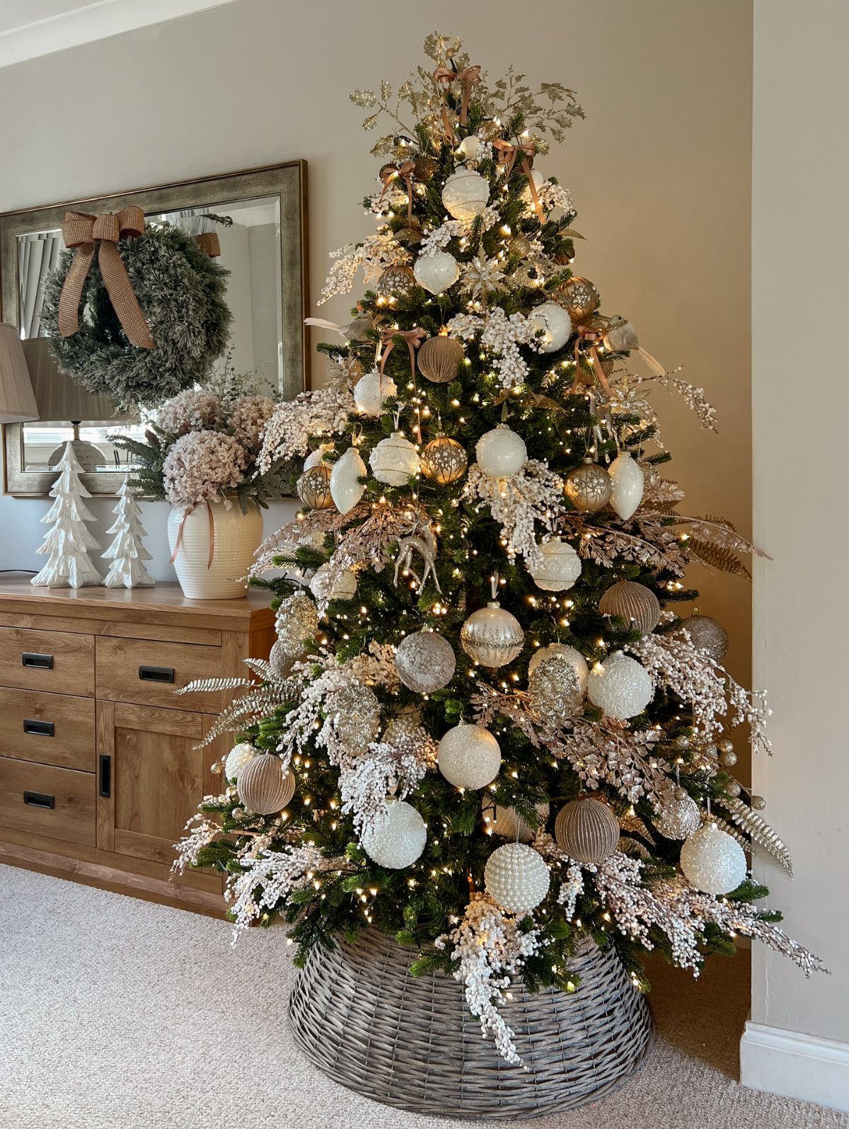 Christmas tree decorated with gold and white ornaments and warm lights in a basket