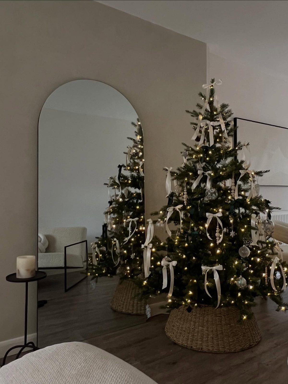 Christmas tree with white ribbons and warm lights in a woven basket base.